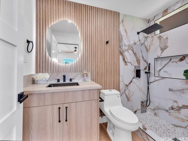 bathroom featuring tiled shower, toilet, vanity, ceiling fan, and hardwood / wood-style floors