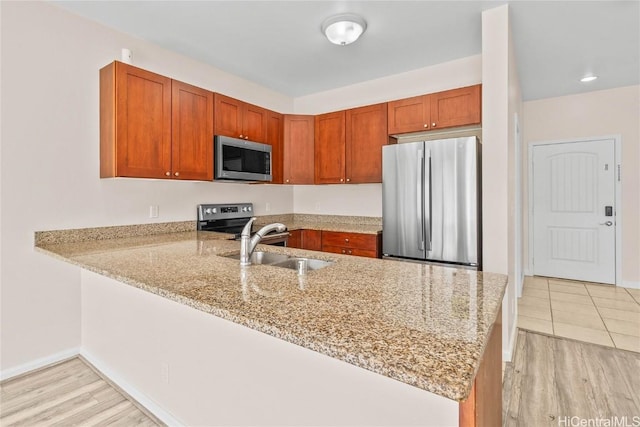 kitchen featuring light stone counters, stainless steel appliances, and kitchen peninsula