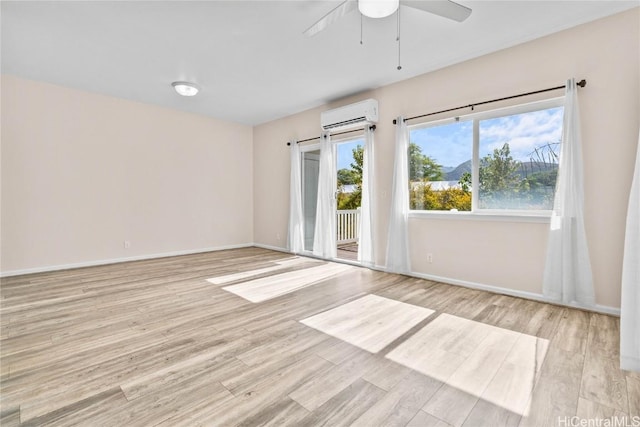 spare room with a wall unit AC, light hardwood / wood-style floors, and ceiling fan