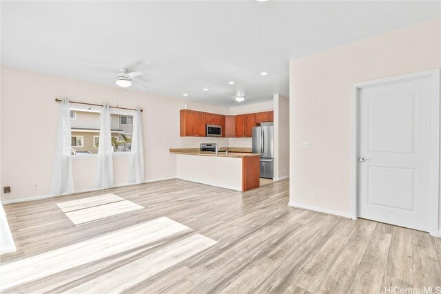 unfurnished living room with sink, light hardwood / wood-style floors, and ceiling fan