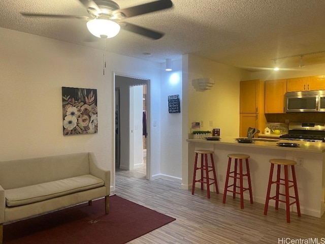 interior space with a breakfast bar area, light hardwood / wood-style floors, a textured ceiling, and appliances with stainless steel finishes