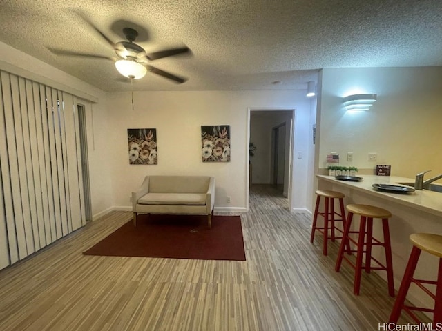 sitting room with ceiling fan, hardwood / wood-style floors, and a textured ceiling