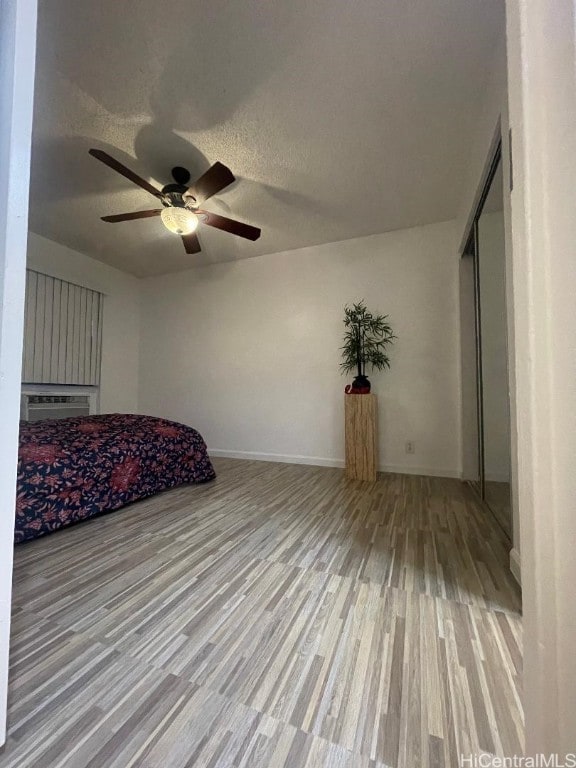 unfurnished bedroom with ceiling fan, a textured ceiling, a closet, and light wood-type flooring