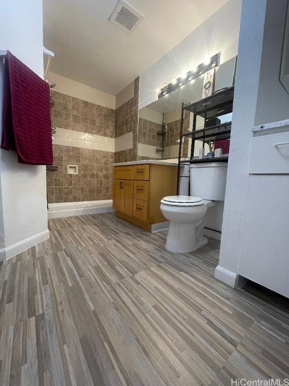 bathroom with hardwood / wood-style flooring, vanity, toilet, and tile walls