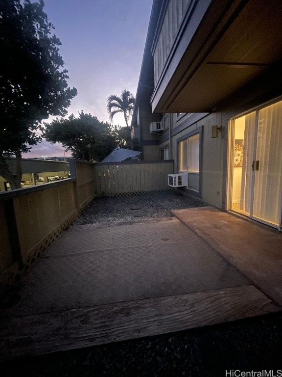 patio terrace at dusk featuring a wall mounted air conditioner