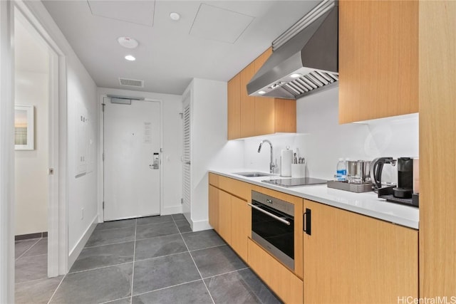 kitchen featuring range hood, black electric stovetop, visible vents, stainless steel oven, and a sink