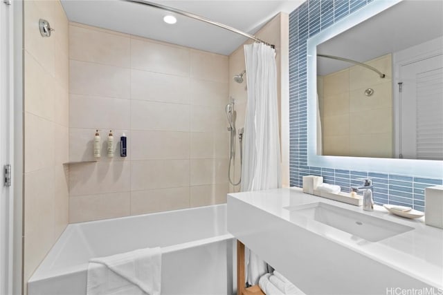 bathroom with shower / bath combo with shower curtain, tile walls, backsplash, and a sink