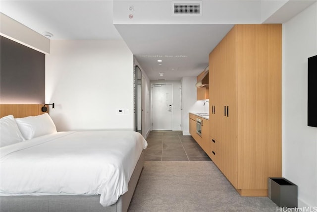 bedroom featuring light tile patterned flooring, a sink, visible vents, and light colored carpet