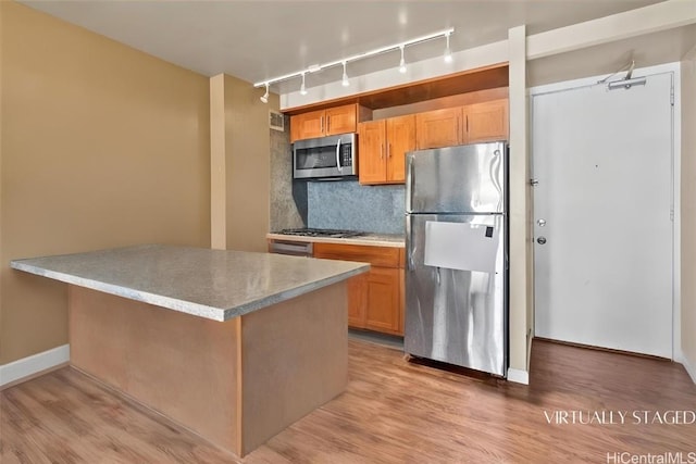 kitchen featuring stainless steel appliances, rail lighting, light hardwood / wood-style floors, and backsplash