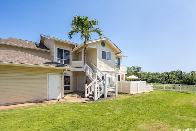 rear view of house featuring a yard, stairway, a patio, and fence