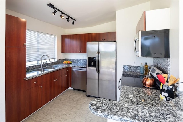 kitchen with light floors, dark stone countertops, appliances with stainless steel finishes, and a sink