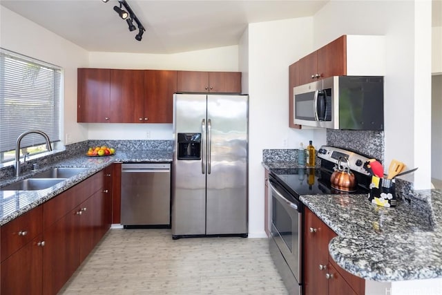 kitchen with dark stone counters, stainless steel appliances, tasteful backsplash, and a sink