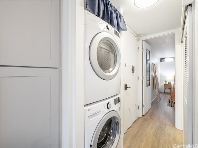 laundry area featuring stacked washer and dryer and light wood-type flooring