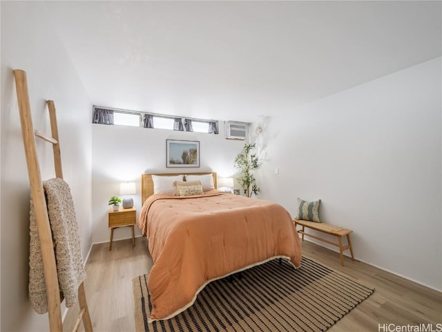 bedroom with a wall unit AC and light wood-type flooring