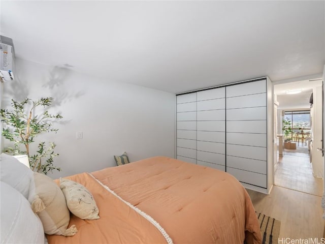 bedroom with an AC wall unit and light hardwood / wood-style flooring