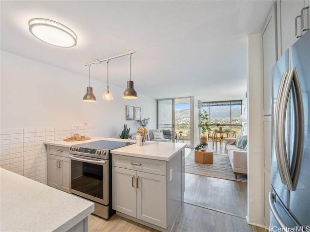 kitchen with a kitchen island, appliances with stainless steel finishes, pendant lighting, floor to ceiling windows, and light hardwood / wood-style flooring