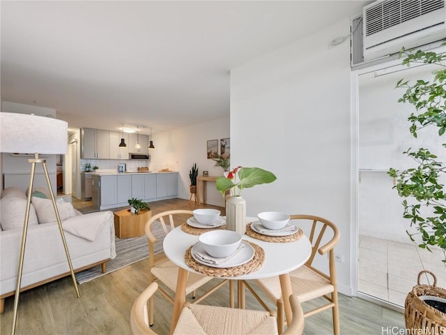 dining space with an AC wall unit and light wood-type flooring