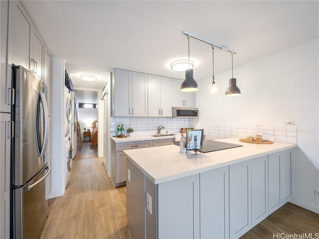 kitchen featuring tasteful backsplash, stainless steel appliances, kitchen peninsula, and hanging light fixtures