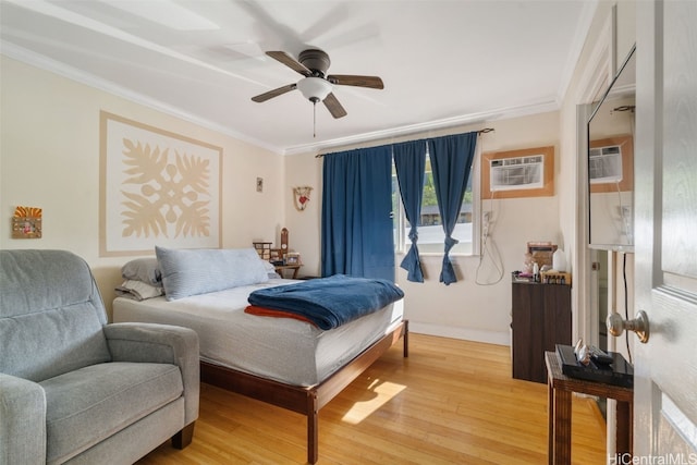 bedroom featuring an AC wall unit, light wood finished floors, a ceiling fan, and crown molding