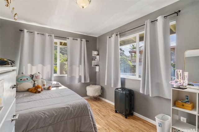 bedroom featuring multiple windows, hardwood / wood-style flooring, and radiator