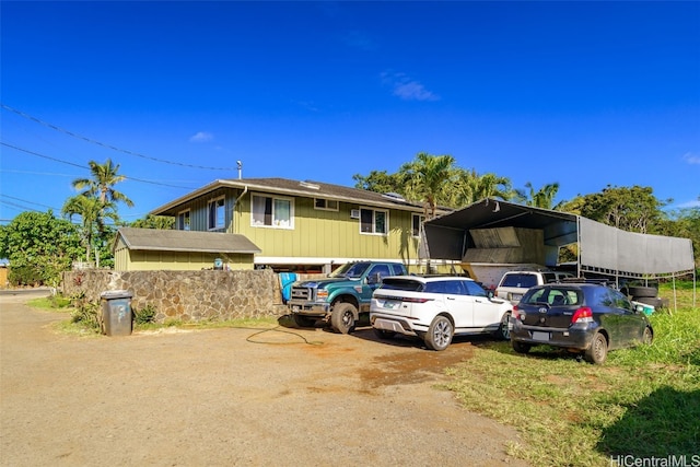 view of front facade with dirt driveway and a detached carport