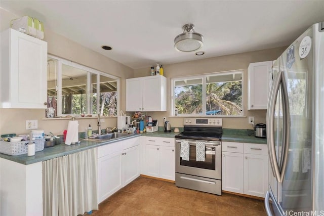 kitchen featuring appliances with stainless steel finishes, a wealth of natural light, white cabinetry, and a sink