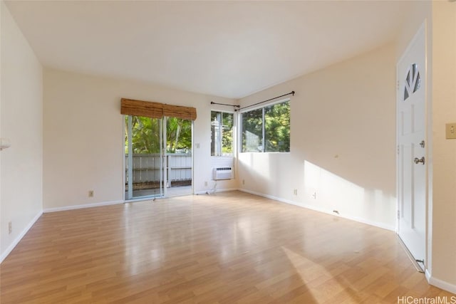 unfurnished room featuring a wall unit AC and light wood-type flooring