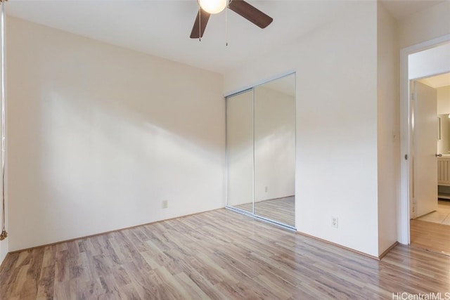 unfurnished bedroom featuring ceiling fan, light wood-type flooring, and a closet