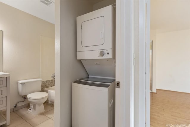 laundry room featuring stacked washer and clothes dryer and light tile patterned floors