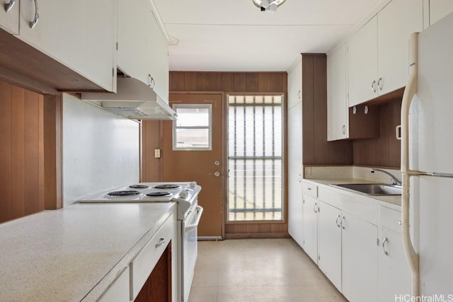 kitchen with wood walls, white cabinetry, sink, ornamental molding, and white appliances