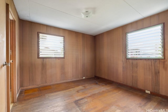 unfurnished room with wooden walls and light hardwood / wood-style flooring