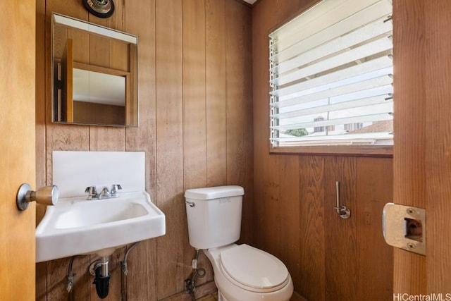 bathroom featuring sink, wooden walls, and toilet