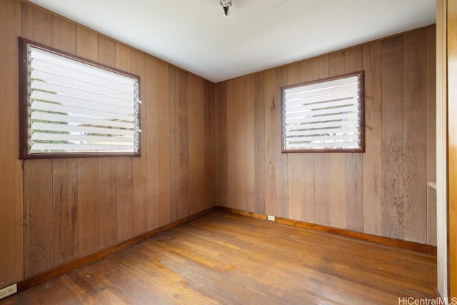 spare room featuring wood-type flooring and wood walls