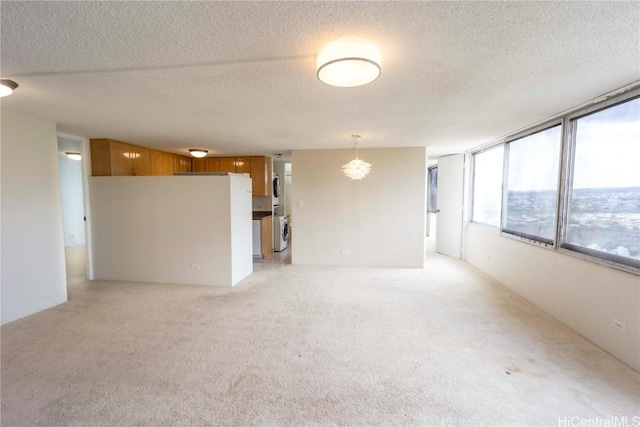 carpeted spare room with stacked washer and dryer and a textured ceiling