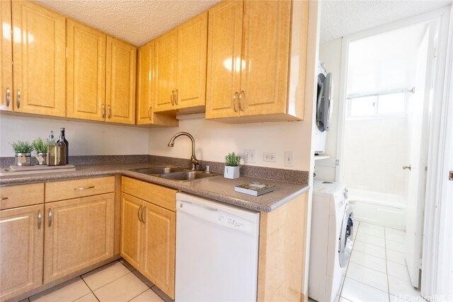 kitchen with light tile patterned flooring, sink, a textured ceiling, washer and dryer, and white dishwasher