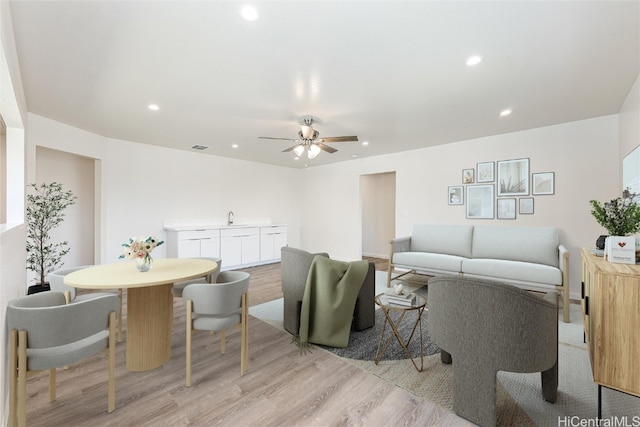 living room featuring ceiling fan, sink, and light hardwood / wood-style floors