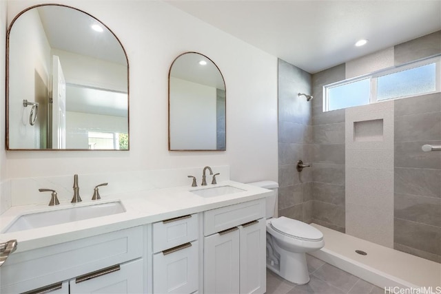 bathroom with tiled shower, vanity, toilet, and tile patterned flooring