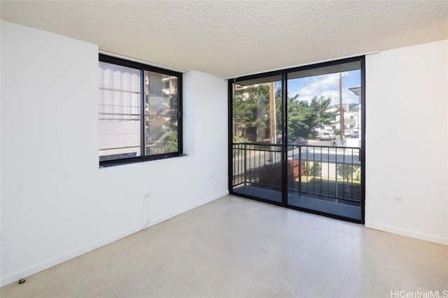 spare room with baseboards, a wall of windows, a textured ceiling, and tile patterned floors