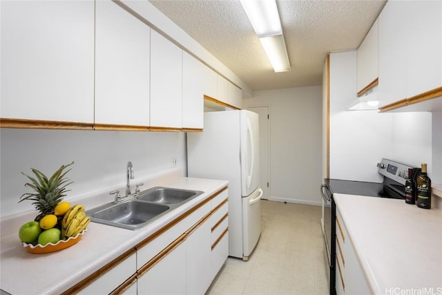 kitchen featuring stainless steel electric range oven, white cabinetry, a sink, and freestanding refrigerator