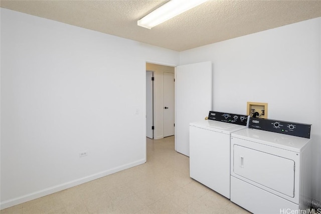 washroom with light floors, washing machine and clothes dryer, a textured ceiling, laundry area, and baseboards