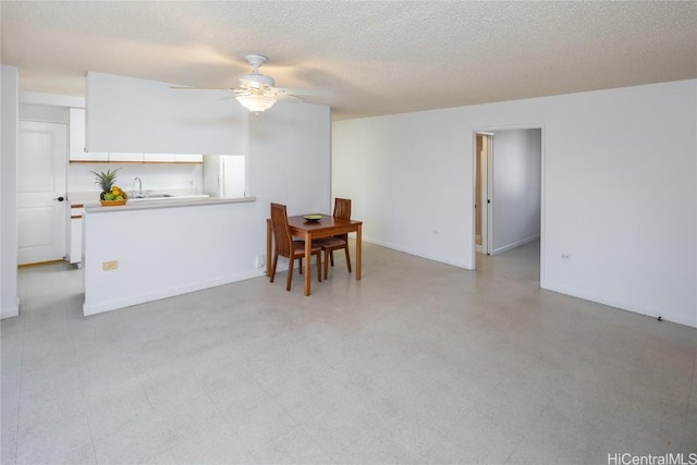 dining room featuring light floors, a textured ceiling, baseboards, and a ceiling fan