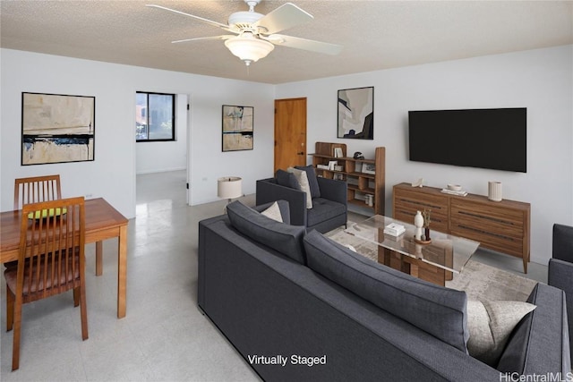 living room featuring ceiling fan and a textured ceiling