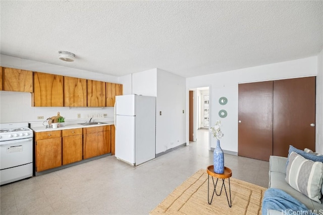 kitchen with sink, white appliances, and a textured ceiling