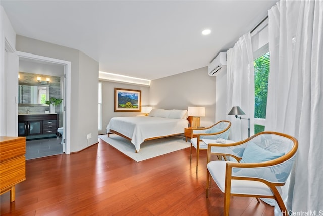 bedroom with hardwood / wood-style flooring, ensuite bath, and a wall mounted AC