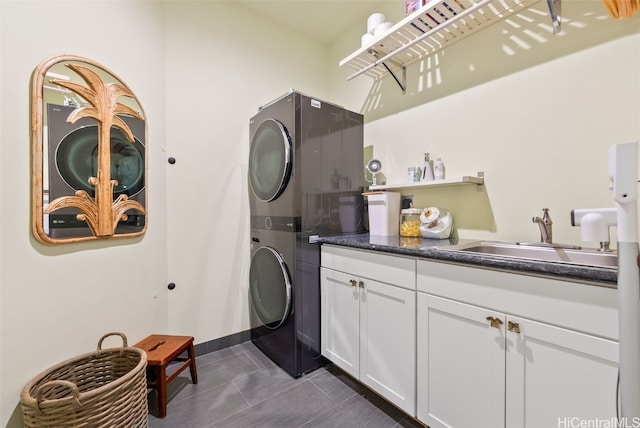 clothes washing area featuring cabinets, stacked washer and dryer, dark tile patterned flooring, and sink