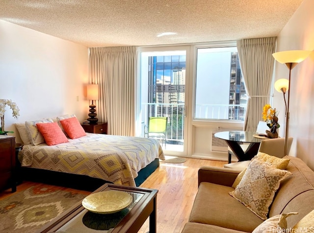 bedroom with multiple windows, a textured ceiling, access to exterior, and light hardwood / wood-style floors