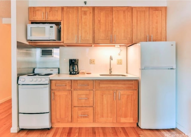 kitchen with white appliances, sink, and light wood-type flooring