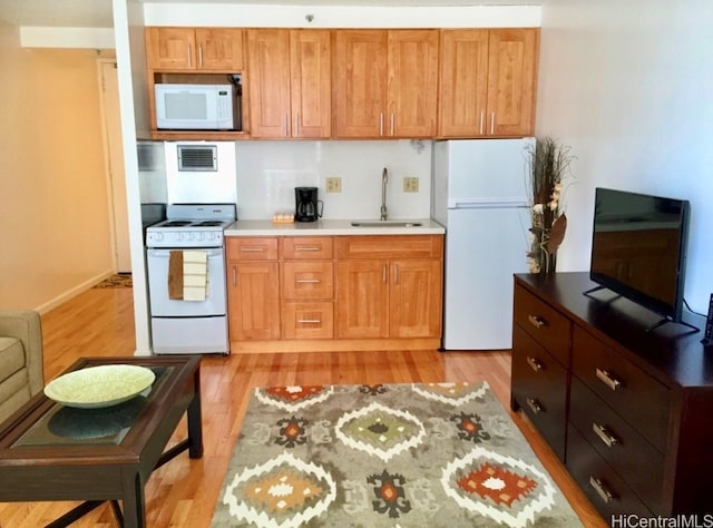 kitchen with white appliances, sink, and light wood-type flooring