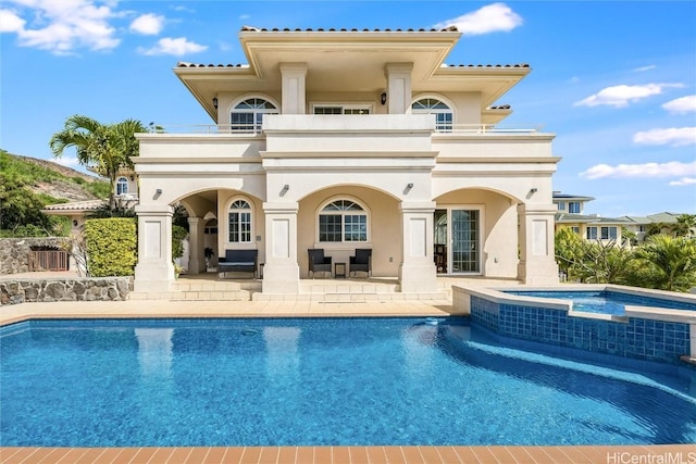 rear view of property featuring a swimming pool with hot tub and a patio