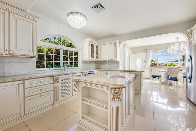 kitchen with sink, hanging light fixtures, light tile patterned floors, cream cabinets, and an inviting chandelier